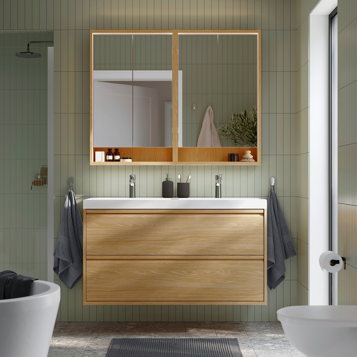 Modern bathroom with large oak cabinet, sleek white counter, and large mirror, surrounded by green tile walls.