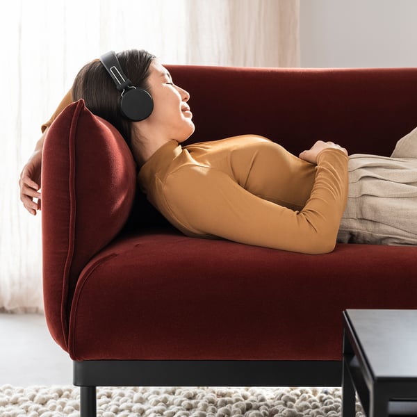 Person on ÄPPLARYD sofa, listening to headphones.