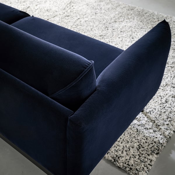 Blue velvet sofa corner, on textured rug.