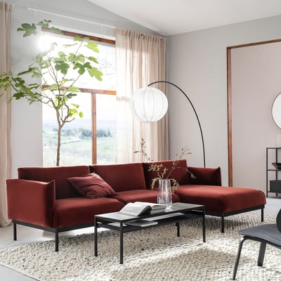 Modern living room an ÄPPLARYD rust-red sofa with sleek design, teammate coffee table, and large window with sheer curtains.
