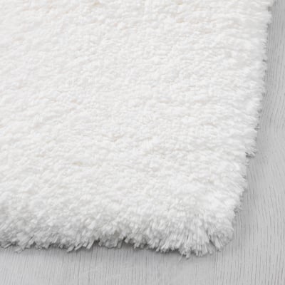 Soft, fluffy white bath mat with plush texture and non-slip backing.