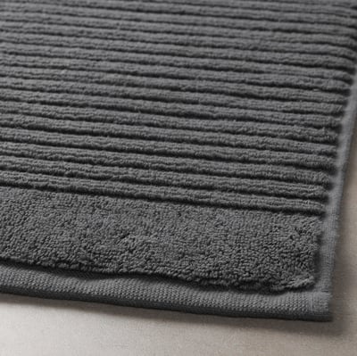 Stacked grey bath mats, textured, neatly folded, soft material.