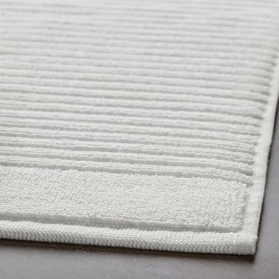 Close-up of plush, white cotton bath mat with intricate texture, showcasing its soft, absorbent material.