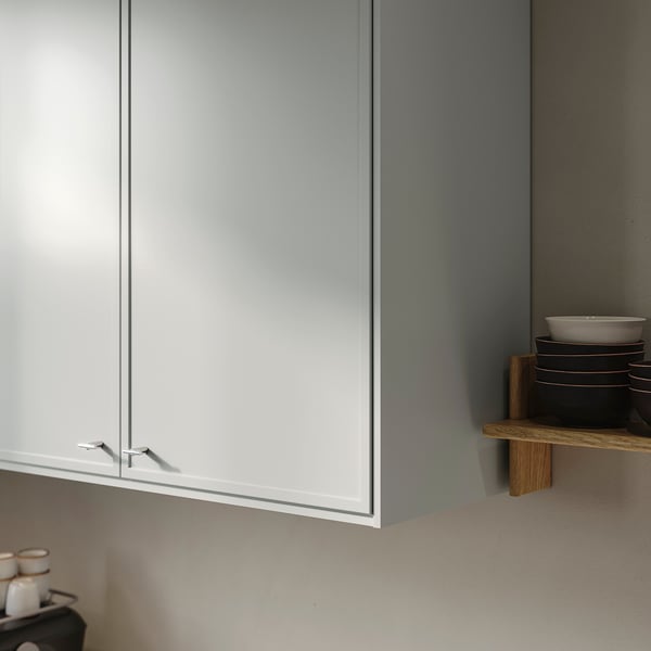 Minimalist kitchen cabinet with thin frame, light grey finish, and stackable plates on a wooden shelf.