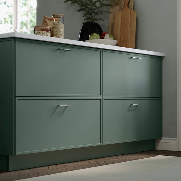 Green askdden cabinets, modern kitchen setup, featuring sleek, minimalist thin frames. Wood floor, white countertop. Smaller than wall plant.