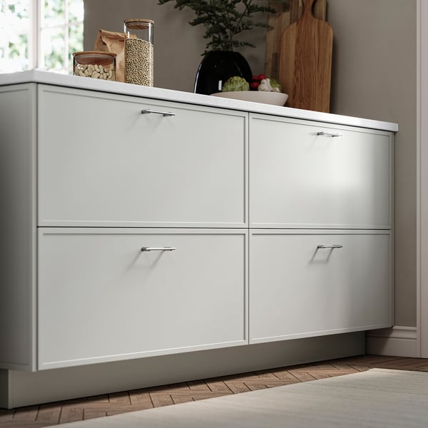 White ASPUDDEN cabinet in kitchen with thin frame design, next to window and decor.