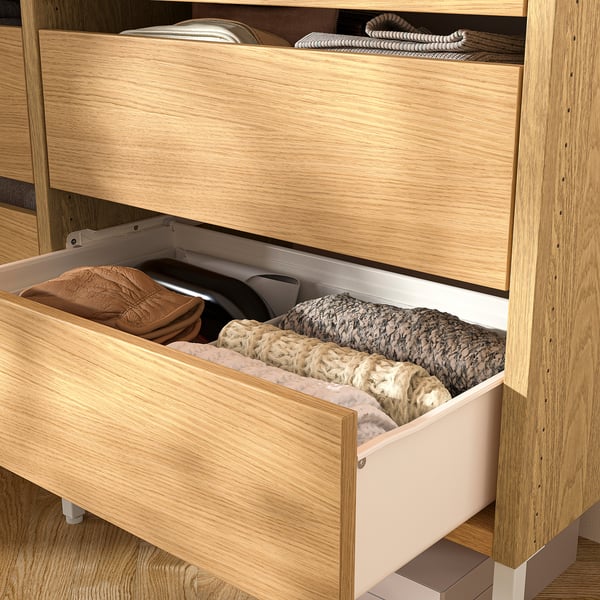 Wooden closet drawers with clothes neatly folded inside, showing organised storage.