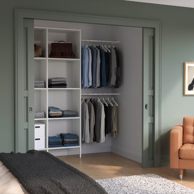 Modern bedroom with AURDAL closet, leather chair, rug, and bed.