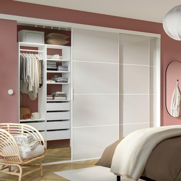AURDAL white storage unit in red room, fitting neatly beside bed, with open shelves, hanging space, and drawers.