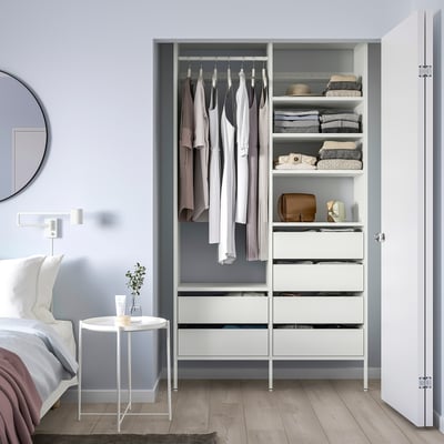 White AURDAL closet with clothes & drawers, next to bed & mirror.