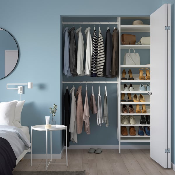 Modern bedroom with AURDAL white storage, hanging rods, shelves, and a calming blue hue.