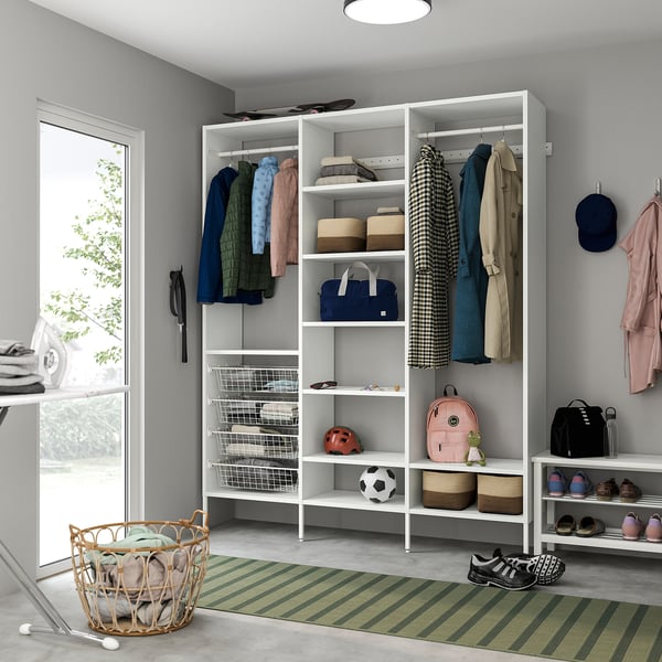 Closet with white AURDAL storage: shelves, clothes, accessories, shoe rack, folded clothes, green rug.