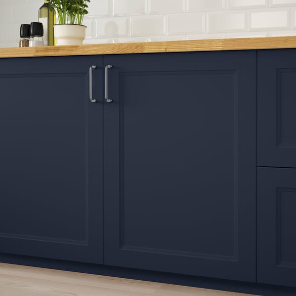 Navy blue kitchen cabinets with silver handles, topped with wooden counter and white tiles.
