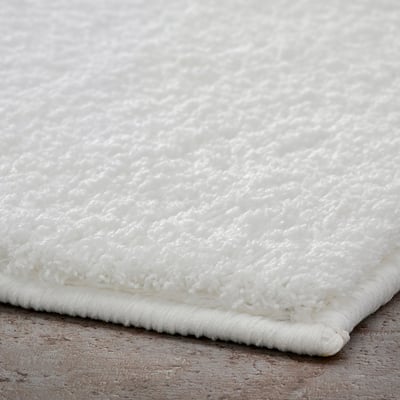Close-up of soft, plush white bath mat, showcasing its thick, textured surface and secure latex backing.