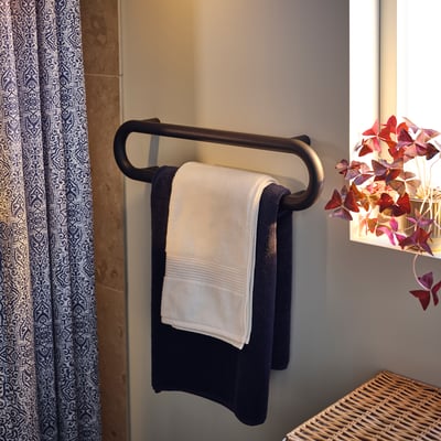 Dark grey towel rail hangs two towels, sleek rounded design.