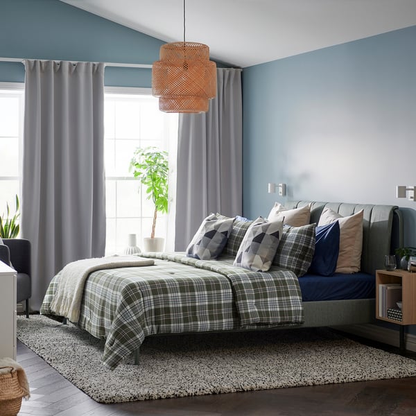 Cosy bedroom with BANBJÖRNBÄR striped bed, soft grey blanket, pillows, blue walls, warm pendant light, plant.
