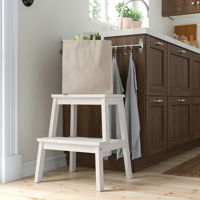 White BEKVÄM step stool in kitchen, solid wood, compact with hand hole, under counter.