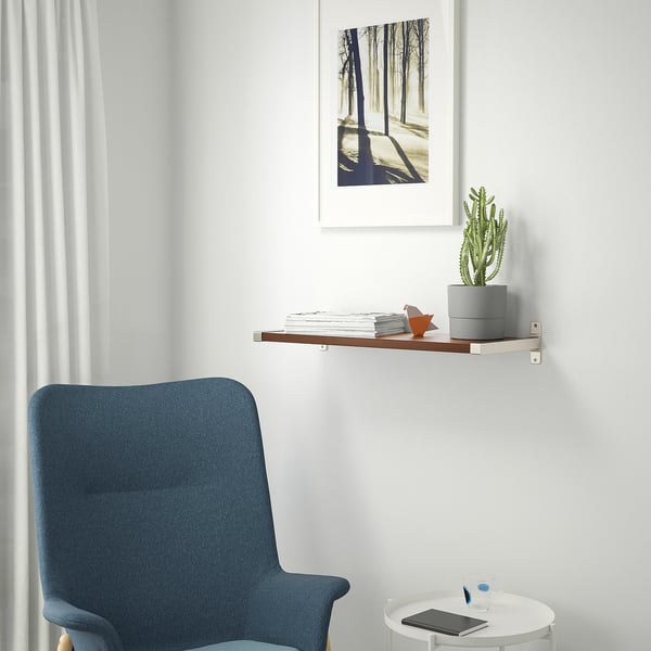 Modern room with blue chair and shelf. BERGSHULT holds books, a cactus, and a fox, complementing white walls and framed trees.