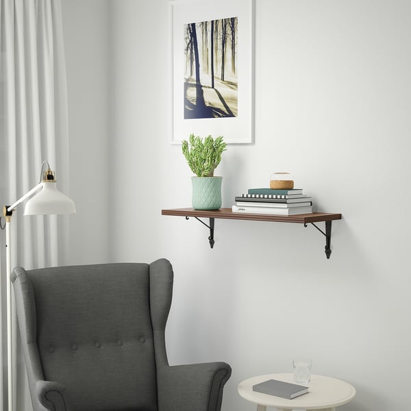 Modern room with BERGSHULT shelf, books, plant, decor, armchair, and artwork.