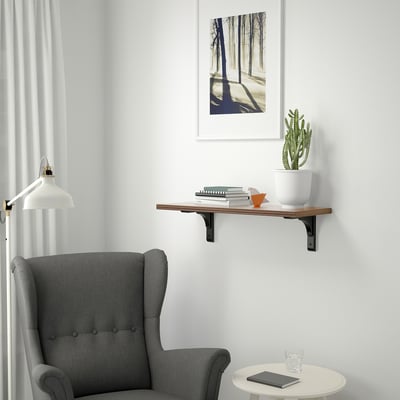 Cosy reading corner with grey armchair, bookshelf, cactus, orange decor, nature print, tablet, glass.