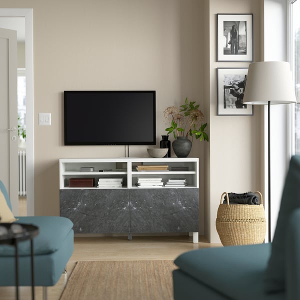 Modern living room with BESTÅ tv bench in white and marble. Flat screen tv, blue and green furniture, decor items, baskets.