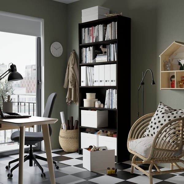 Home office with BILLY bookcase, desk, lamp, city view, wicker chair.