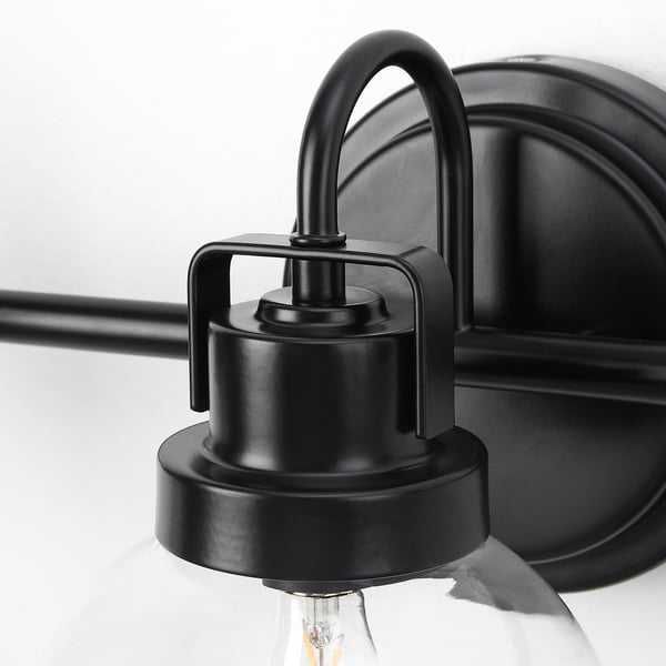 Black metal wall lamp with clear glass shade, showcasing mouth-blown craftsmanship.