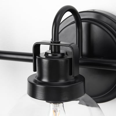 Black metal wall lamp with clear glass shade, showcasing mouth-blown craftsmanship.