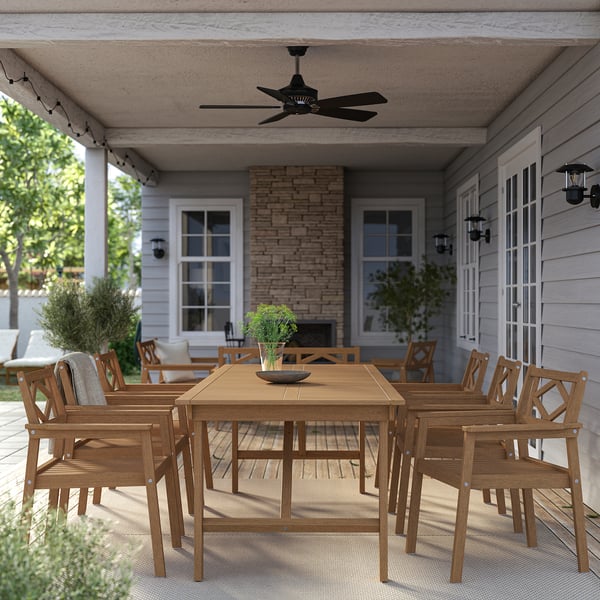 Wooden outdoor dining set with table, 8 chairs on porch.