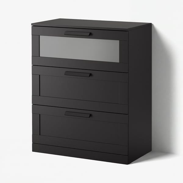 A modern black BRIMNES chest of drawers with four drawers and a frosted glass top drawer, featuring sleek handles and a minimalist design.