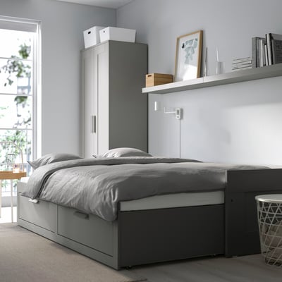 BRIMNES grey day-bed with large storage drawers, compact yet spacious for small rooms, with side table and lamp.