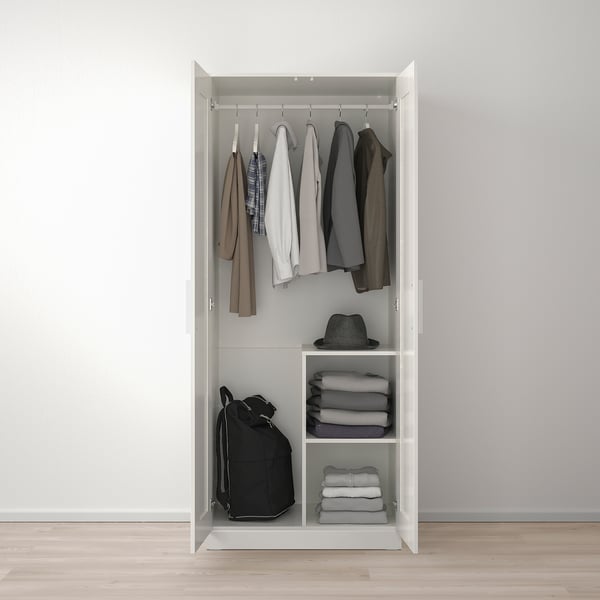 Open wardrobe with clothes rail and shelves. Holds shirts, dresses, and folded garments like sweaters and pants.