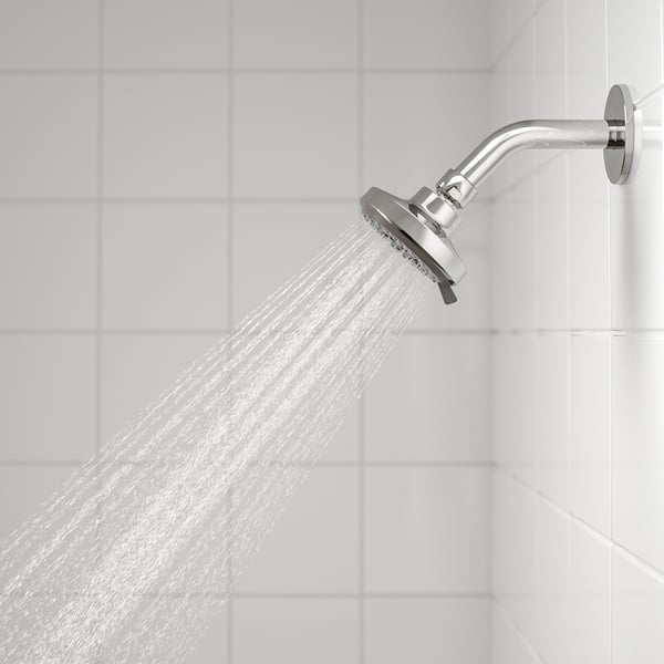 Shower head with full spray function in use. Wide water coverage shown on white tiled wall.
