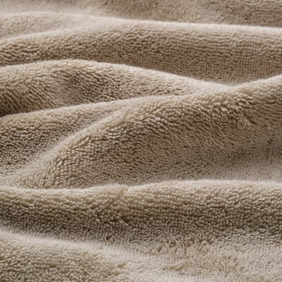 Close-up of plush, organic cotton towel, showcasing its thick, soft texture and elegant woven border.
