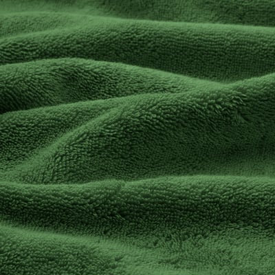Soft, plush green organic towels neatly folded, showcasing their thick, absorbent texture and elegant woven border.