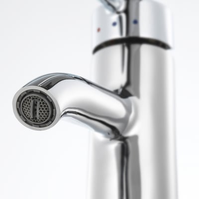 A modern, chrome-plated tap with a honeycomb aerator, mounted on a sleek, vertical white panel. The design is elegant and durable.