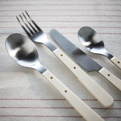 Elegant cutlery set with gold-tone accents on striped fabric.