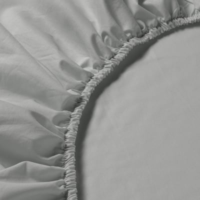 Fitted sheet with elastic hem, made of soft, breathable cotton, displayed on a bed.