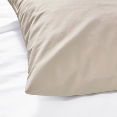 Close-up of a soft, smooth, beige DVALA pillowcase, likely made of 100% cotton, resting on a white surface.