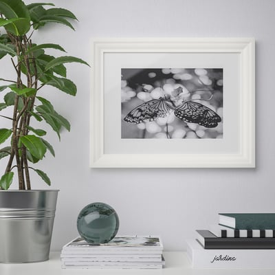 Framed black-and-white butterfly picture hangs on wall, surrounded by decorative items.