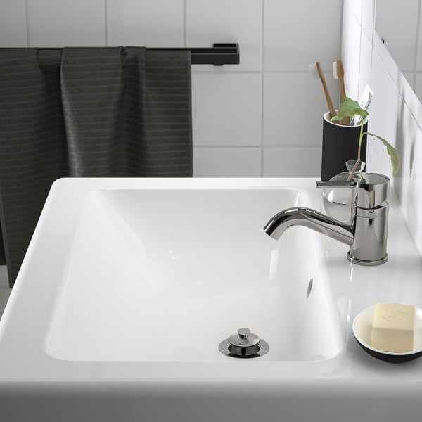 Modern bathroom sink with chrome tap, toothbrush holder, and soap.