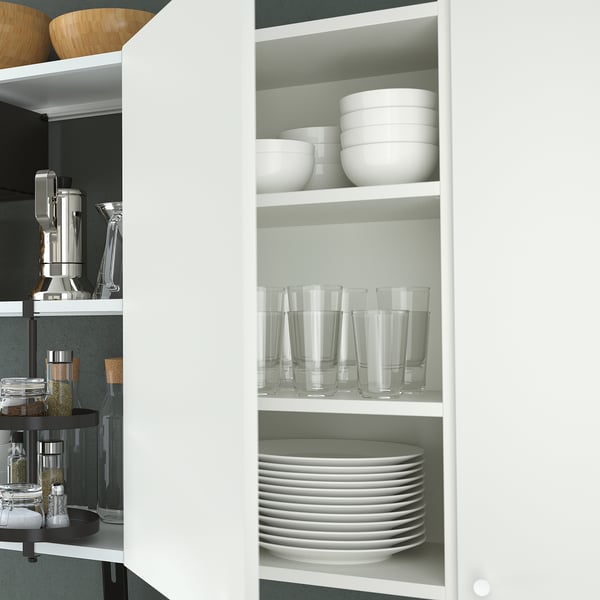 Open white cabinet reveals stacked bowls, glasses, and plates on shelves, storing kitchen items neatly.