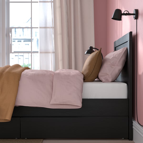 Cosy bed with pink linens, wall light, and city view.