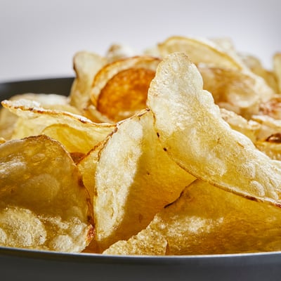 A bowl of golden, crispy potato chips with the skin on, ready for snacking.
