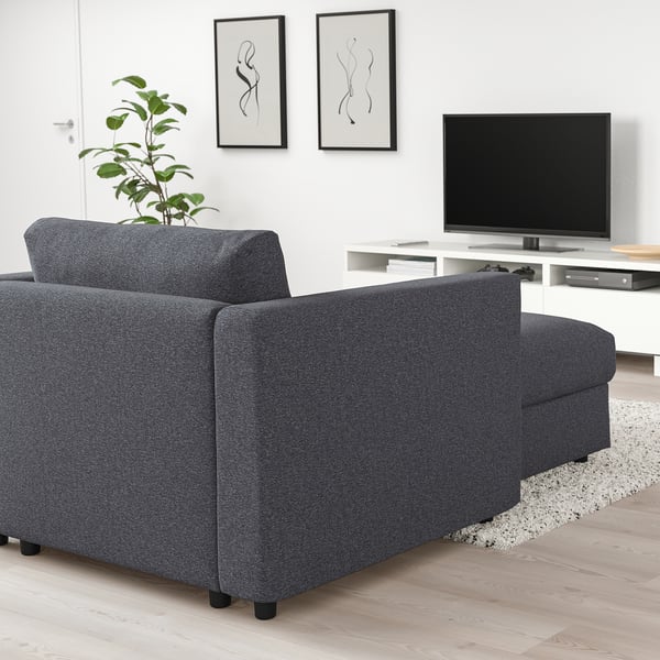 Dark grey FINNALA sectional sofa with chaise, modern design, large seating, flat-screen tv, abstract art, potted plant.