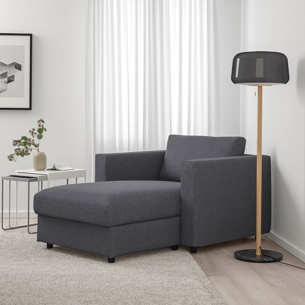 Modern cosy corner: dark grey FINNALA sectional sofa with ottoman, plus tall floor lamp. Comfortable & stylish, fits neatly in space.