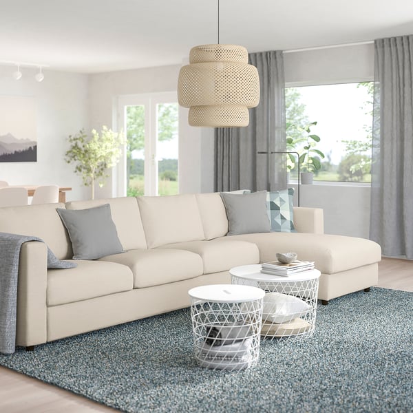 Modern living room with FINNALA sofa, cushions, coffee tables, blue rug, large windows, and light fixture.