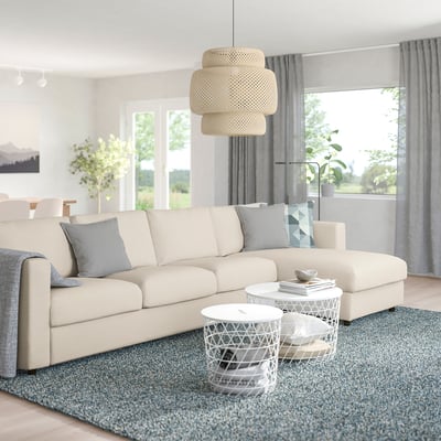Modern living room with FINNALA sofa, cushions, coffee tables, blue rug, large windows, and light fixture.