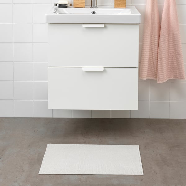 Modern bathroom with white FINTSEN mat, sink, and towel. Mat is rectangular, fits under sink, made of recycled polyester.