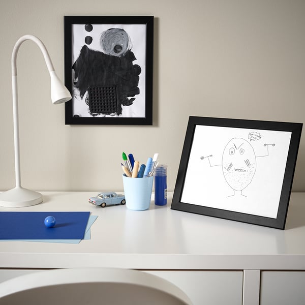 White desk with kids drawing, lamp, pencils, toy car.